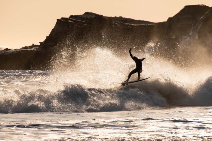 Surfer at Año Nuevo Reserve Flying Off a Wave with Arms Overhead